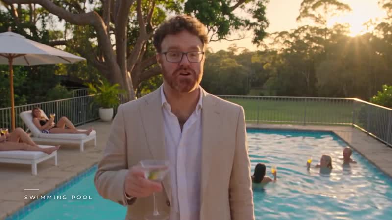 The host stands by the pool at golden hour with swimmers and sunbathers behind him.