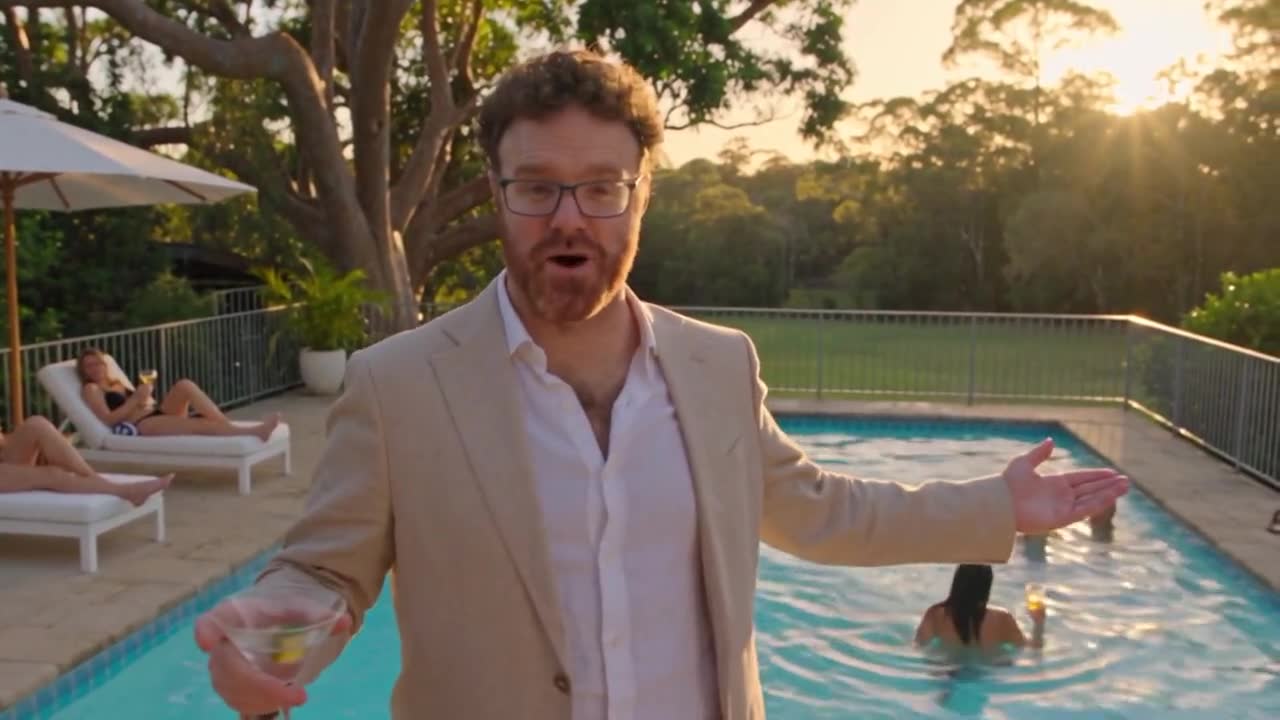 Blake McIntyre, hosting by the pool at golden hour with a cocktail in hand.